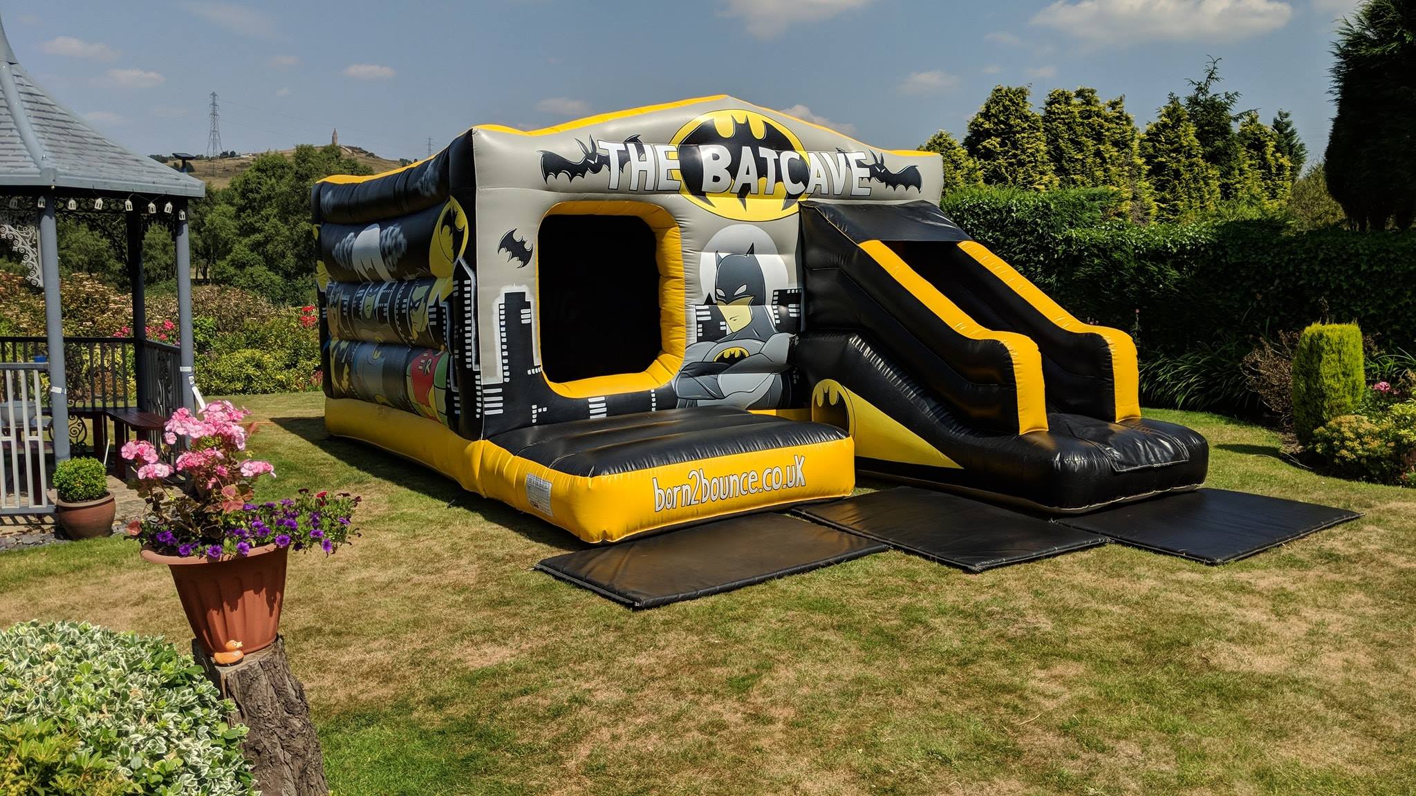 Superhero themed Batcave bouncy castle with front slide setup in a Bramhall garden, SK7.